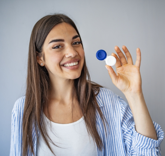 Junge Frau hält Kontaktlinsenaufbewahrungsbehälter in die Kamera. 